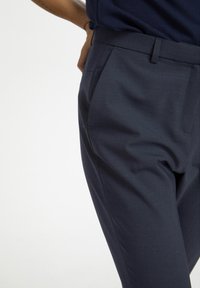 Marineblauwe op maat gemaakte broek van gladde stof, met een platte voorkant, zijzakken en een strakke pasvorm.