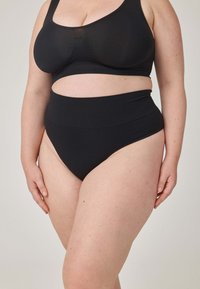 Czarny komplet bielizny, w skład którego wchodzi braletka z dekoltem w kształcie litery U oraz majtki z wysokim stanem. Materiał wydaje się miękki, o gładkiej fakturze i minimalistycznym designie.