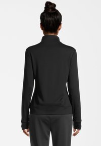 Giacca sportiva nera a maniche lunghe con colletto alto e texture liscia. Presenta un design aderente e cuciture piatte, adatta per l'abbigliamento attivo.