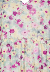 Robe fleurie avec une base jaune doux ornée de fleurs roses et violettes, détail de taille à volants et design en V. Le tissu paraît léger et texturé.