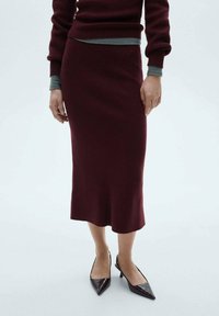 Gonna midi in magenta a maglia con una silhouette aderente, caratterizzata da una texture a coste e un orlo discreto. Abbinata a tacchi in pelle scuri e appuntiti.