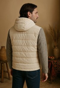 Lichte gewatteerde vest, met een crèmekleurige voorkant met horizontale padding, grijze gestructureerde mouwen, een vast capuchon en een casual pasvorm.