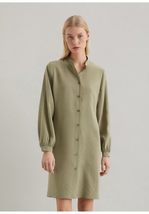 Olijfgroene shirtjurk met een staande kraag, lange ballonmouwen en een sluiting met knopen aan de voorkant. Zachte stof met een subtiele textuur.