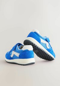 Niebieskie buty sportowe z zamszu i siateczki z białymi akcentami, z rzepami oraz teksturowaną czarną gumową podeszwą, ustawione pod kątem dla lepszej widoczności.