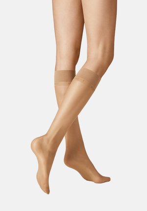 Kniestrümpfe in einem nude Farbton mit glattem, transparentem Finish und einem gerippten oberen Bund, der dezente Branding-Elemente aufweist.