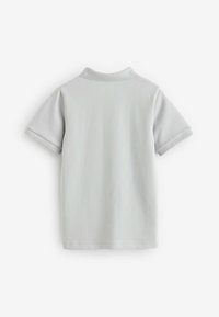 Polo à manches courtes gris clair vu de dos, avec un col simple et sans logo ni motif visible.