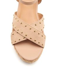 Sandalo con zeppa in suede nudo, con cinturini incrociati e dettagli in oro, dotato di una suola piatta liscia e una suola in iuta intrecciata.