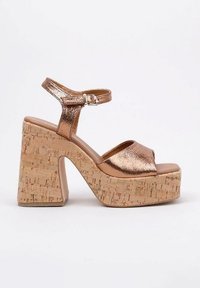 Sandalias de plataforma metálicas en color rosa oro, con una amplia base de corcho, cinta en el tobillo y diseño de punta descubierta. Textura suave con forma redondeada.