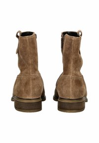 Une paire de bottines en daim marron avec de petits talons empilés, des boucles à l'arrière et des zips sur les côtés, montrées de l'arrière sur un fond blanc.