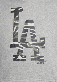 Grå sweatshirt med en stor "LA"-logotyp i camouflage-mönster med gröna, svarta och vita ränder, tryckt på ett texturerat tyg.