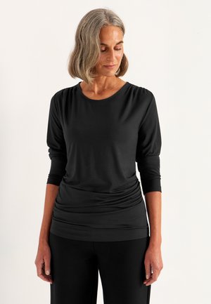 Zwarte longsleeve top met een ronde halslijn, voorzien van geplooide details op de schouders en een gerimpelde taille, gemaakt van zachte, rekbare stof.