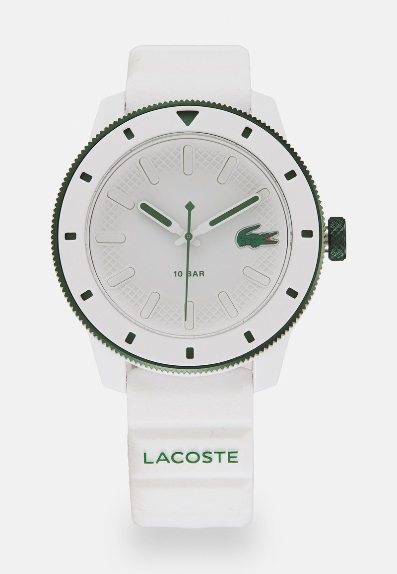 Λευκό ρολόι με πράσινες λεπτομέρειες, με υφή στη διάταξη του καντράν, μεγάλες ενδείξεις ωρών και ανθεκτικό λουρί από καουτσούκ με ανάγλυφο το "LACOSTE."