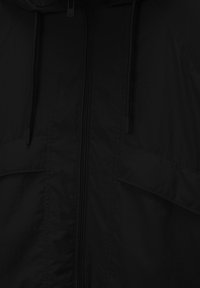 Veste noire zippée en matériau léger, dotée d'une capuche, de cordons et de deux poches avant. Texture lisse avec peu de détails.