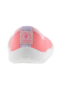Zapato slip-on textil rosa con una suela flexible blanca. Presenta una pestaña en el talón de color lavanda con un parche de logo. Superficie lisa y forma redondeada.