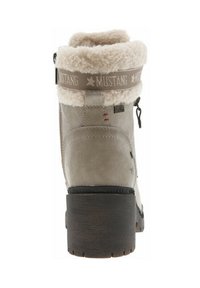 Botte grise haute avec une surface texturée, doublure en fausse fourrure en haut et un talon en cuir brun robuste. Caractéristiques d'une bande logo et de détails de couture subtils.