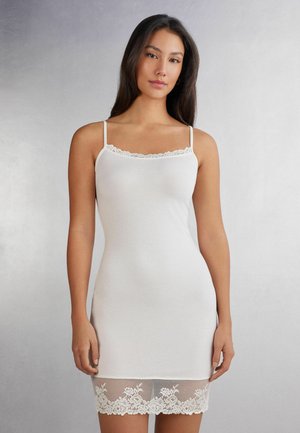 Witte cami-jurk met dunne bandjes, voorzien van een geschulpte kanten rand bij de halslijn en een kanten zoomdetail aan de onderkant. Gladde textuur.