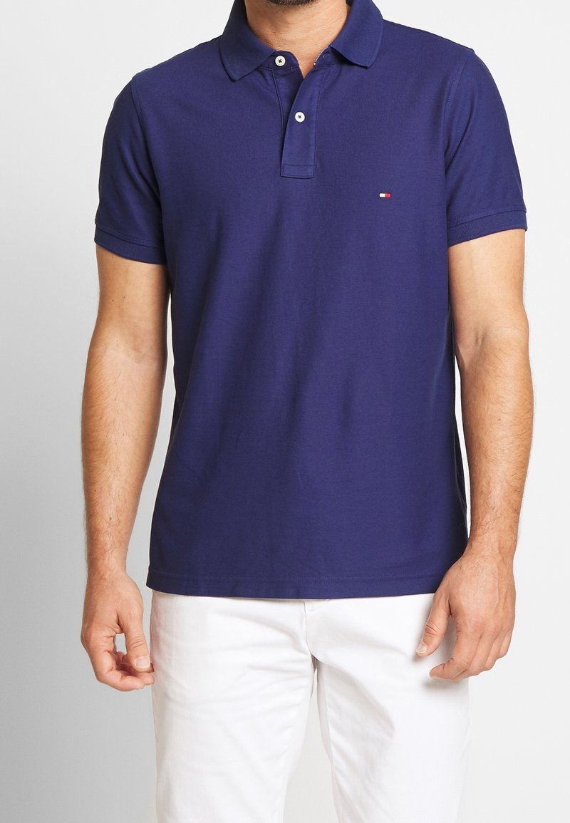 Polo-shirt bleu marine en coton avec un col, des manches courtes et une patte de boutonnage à trois boutons ; caractérisé par un petit logo sur la poitrine.