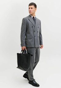 Szary dwurzędowy garnitur z teksturowanej tkaniny, w połączeniu z czarną skórzaną torbą typu tote i czarnymi eleganckimi butami, na tle jednolitego tła.