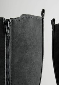 Black faux leather knee-high boots featuring a side zipper closure, smooth texture, and neat stitching along the seams.