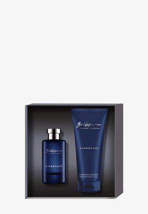 Coffret cadeau avec flacon de Cologne Baldessarini Signature et gel douche assorti, ainsi qu'un tube de shampooing dans un emballage bleu foncé.