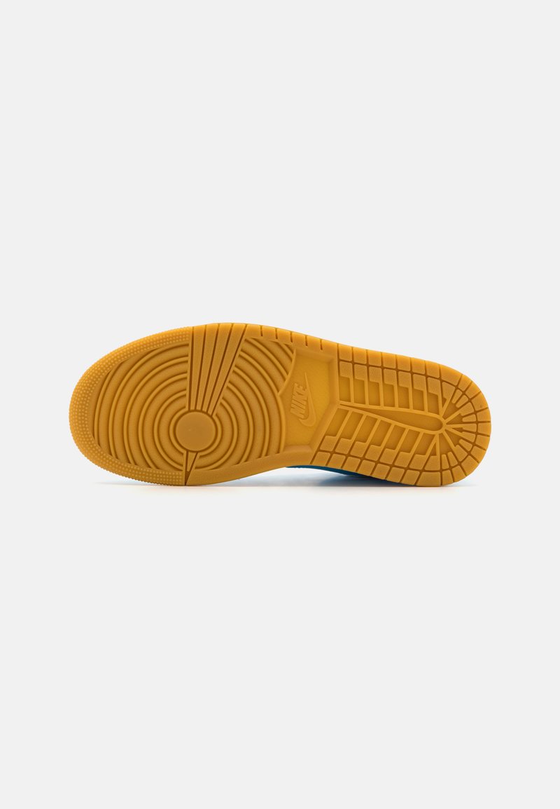 La suola delle scarpe Nike in gomma presenta un motivo circolare, scanalature testurizzate e il marchio. Il colore è arancione con una finitura opaca e un battistrada distintivo.