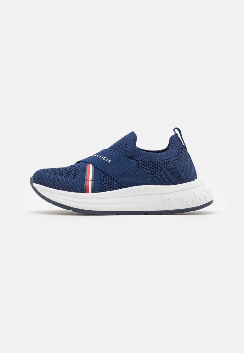 Marineblaue sportliche Sneaker mit atmungsaktivem Strickobermaterial, elastischem Kreuzgurt, roten und weißen Akzenten, weißer Sohle und strukturiertem Fersenbereich.