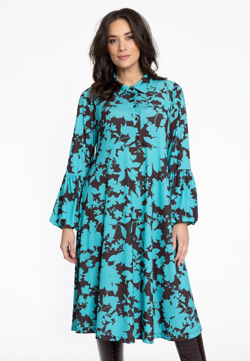 Fließendes schwarzes Kleid mit einem lebhaften türkisfarbenen Blumendruck, einem geknöpften Kragen und ausgestellten Ärmeln, aus leichtem Stoff gefertigt.