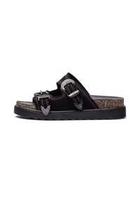 Sandalo aperto in suede nero con due fibbie in argento, dettagli in cuciture rosse e una soletta in sughero testurizzato. Suola in gomma nera spessa con scanalature.