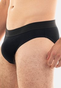 Schwarze Herrenunterhosen mit glatter, weicher Textur und einem breiten Bündchen, das dezente Markenkennzeichnung aufweist. Mit einem klassischen Schnitt entworfen.