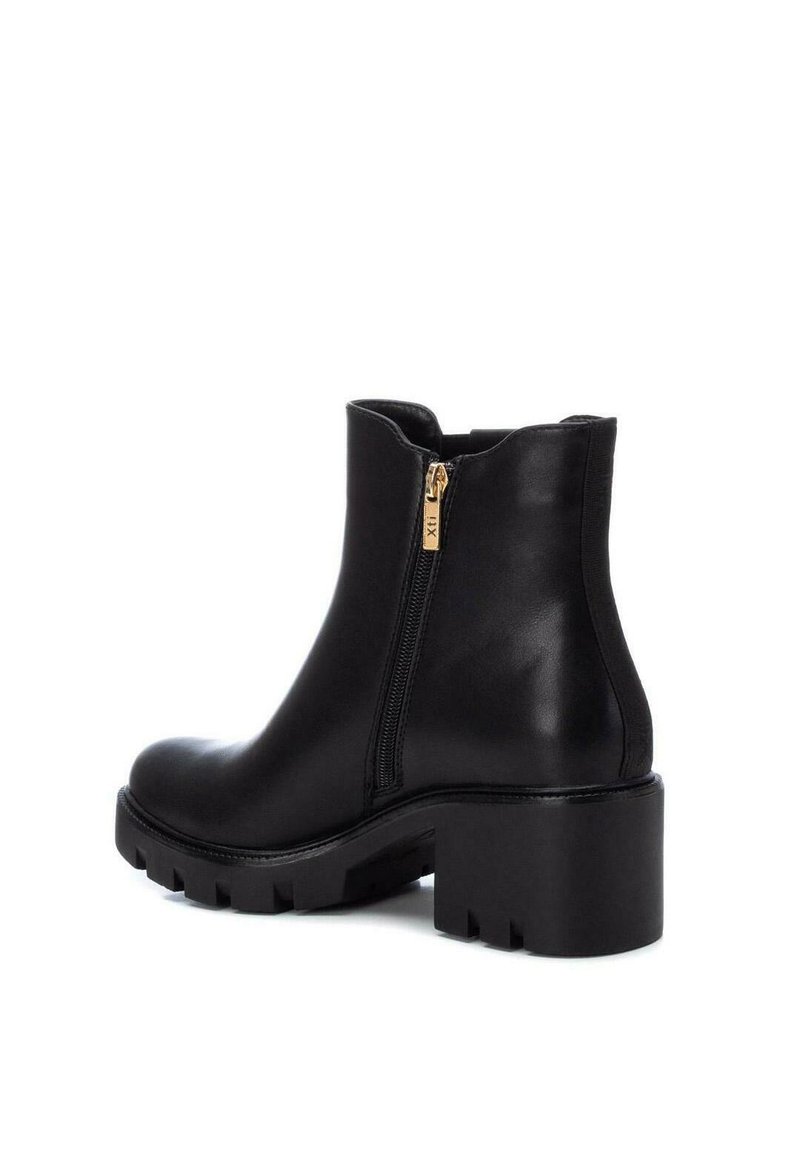 Schwarze Leder-Stiefelette mit dickem Absatz, strukturiierter Sohle und goldfarbenem Seitena zipper auf weißem Hintergrund.