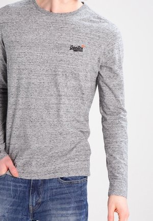 Camisa de manga larga gris hecha de tejido suave con cuello redondo, que presenta un pequeño logo negro en el pecho y una textura sutil.