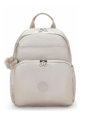 Hellbeiger Rucksack mit vorderer Reißverschlusstasche, zwei Reißverschlussanhängern, rundem Logo-Patch und einem kleinen Plüsch-Affen-Schlüsselanhänger an der Seite.