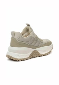 Beige sneaker met een gequilt ontwerp, zachte binnenvoering en een chunky witte zool met gestructureerde rubberen accenten.