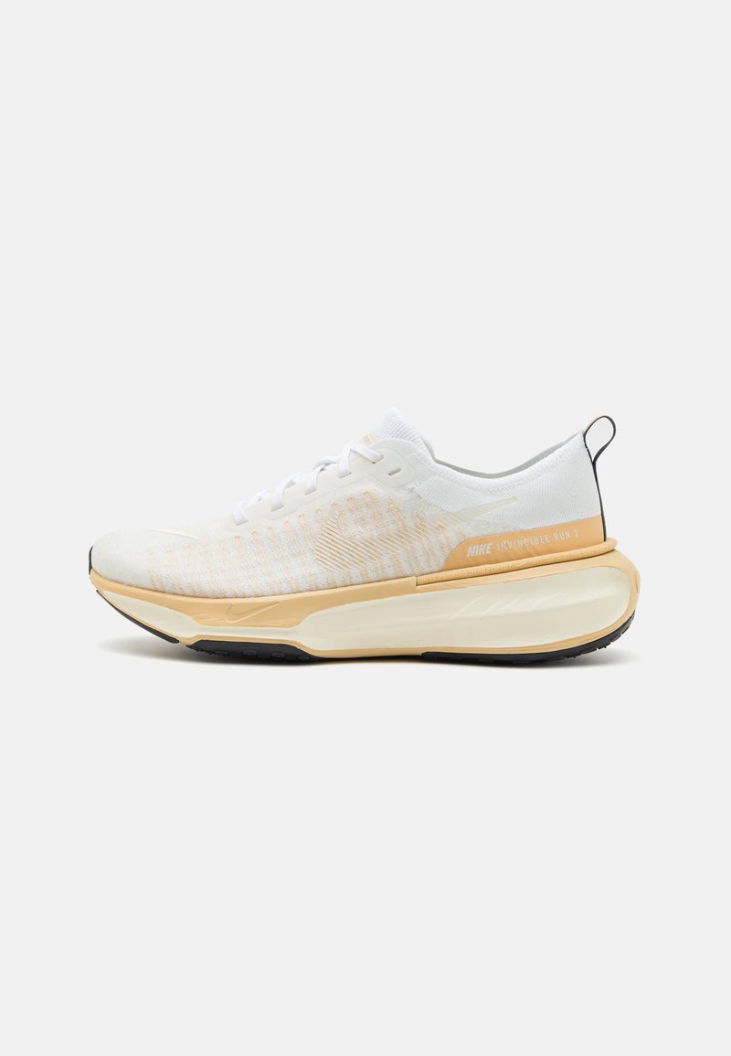 Baskets de course blanches avec une tige en tricot texturé, une semelle intermédiaire jaune rembourrée, une semelle extérieure noire et une boucle au talon pour une mise en chaussure facile.