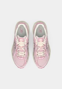 Roosa ja valge New Balance'i jooksujalatsite paar vaadatuna ülalt lihtsa valge tausta peal.