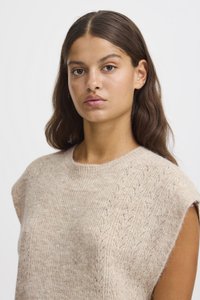Beige rövid ujjú kötött pulóver, puha, texturált anyagból készült, amely finom mintával rendelkezik a vállvarrás mentén.