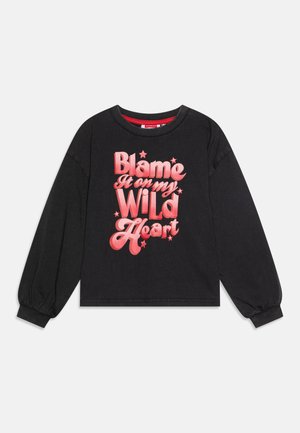 Black cropped sweatshirt with long sleeves featuring large pink text reading “Blame It on my WILD Heart” and small star accents.