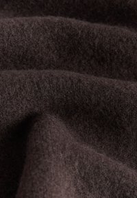 Tissu en laine brun foncé doux avec une surface duveteuse, texturée et des plis doux.
