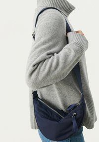 Borsa a tracolla blu navy realizzata in tessuto, con un design curvo, scomparti multiple con zip e una tracolla regolabile.