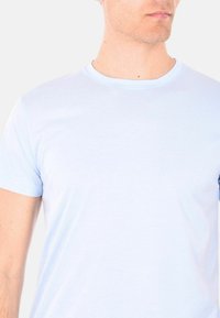 T-shirt a maniche corte di colore azzurro chiaro, realizzato in cotone morbido, con scollatura a girocollo e una texture liscia, adatto per un look casual.