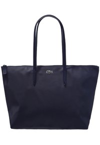 Námořnická modrá tote bag s texturovanou látkou, dvěma dlouhými rukojeťmi a malým vyšitým logem vpředu. Uzávěr na zip nahoře.