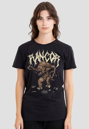 Woman with brown hair wears black Star Wars T-shirt featuring a snarling Rancor creature with stylized text above.