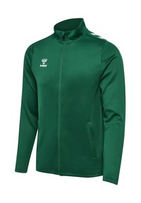 Grön zip-up jacka av slät tyg. Har hög krage, sidofickor och vit logotyp på bröstet med vita detaljer på axlarna.