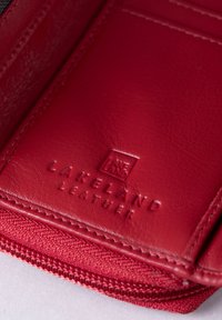 Red leather wallet with embossed "Lakeland Leather" logo, textured surface, and visible stitching along the edge. Zipper detail at the bottom.