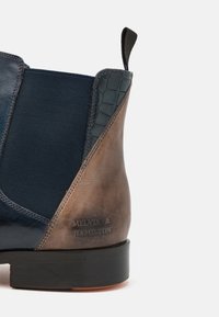 Botine Chelsea din piele bleumarin, cu un panou texturat maro, elastic pe laterale și logo embosat. Talpă solidă din cauciuc negru.