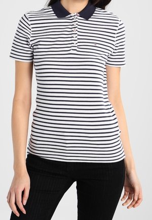 Polo shirt rayé en blanc et bleu marine avec col, boutons et manches courtes. Le tissu semble lisse et ajusté.