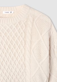 Beżowy sweter dzianinowy z teksturowanym wzorem, w tym sploty warkoczowe i kształty diamentów. Okrągły dekolt i ściągacze przy mankietach. Rozmiar S.