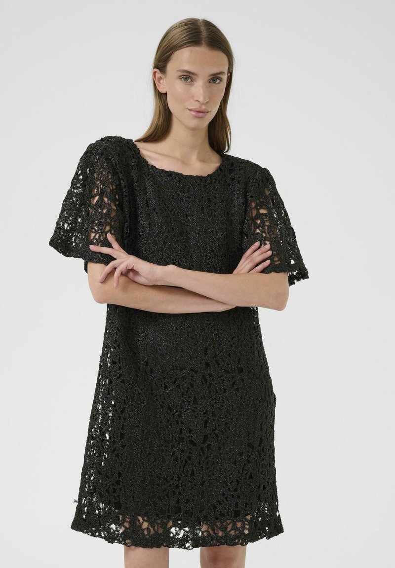 Abito in pizzo nero con maniche corte, caratterizzato da intricati motivi floreali e orlo scallopato. Il tessuto testurizzato aggiunge profondità al design.