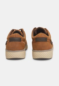 Braune Wildlederschuhe mit einer strukturierten beigen Sohle. Mit einem glatten braunen Akzent in der Nähe der Ferse und einem flachen Design. Stylisch und funktional.