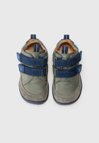 Grüne Leder- und graue Wildlederschuhe für Kinder mit marineblauen Klettverschlüssen, einer Gummisohle und einem blauen Akzent an der Ferse.